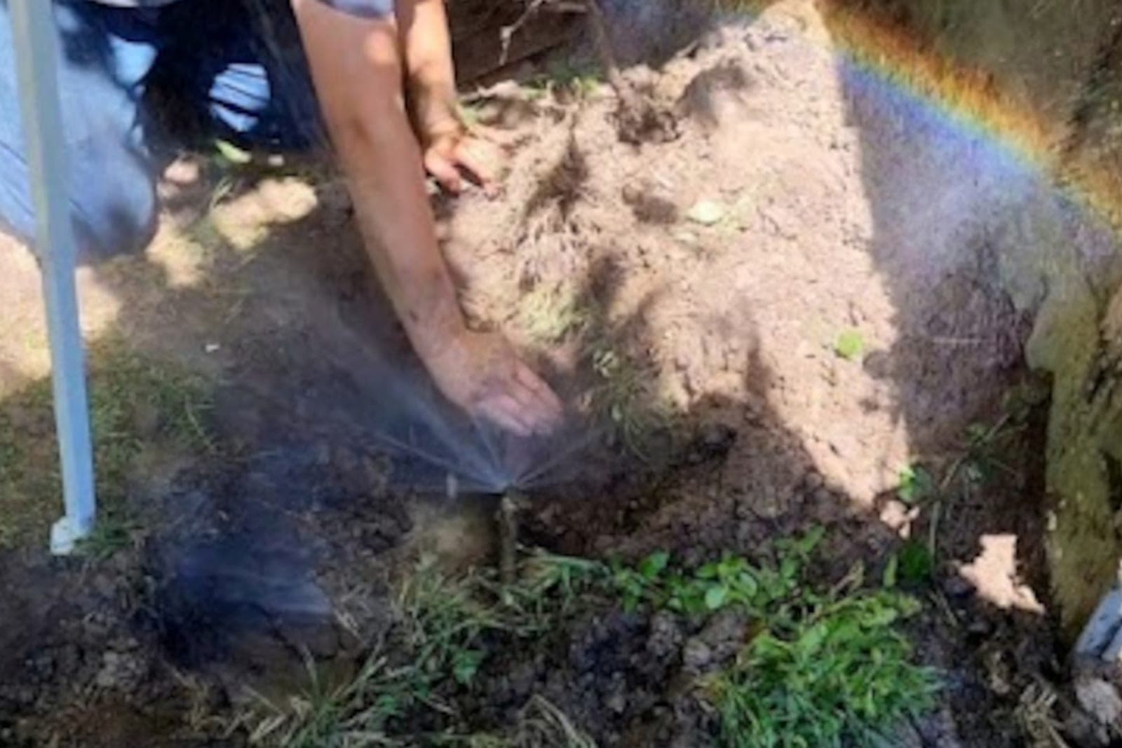 Water spraying from a broken underground water line during an emergency repair